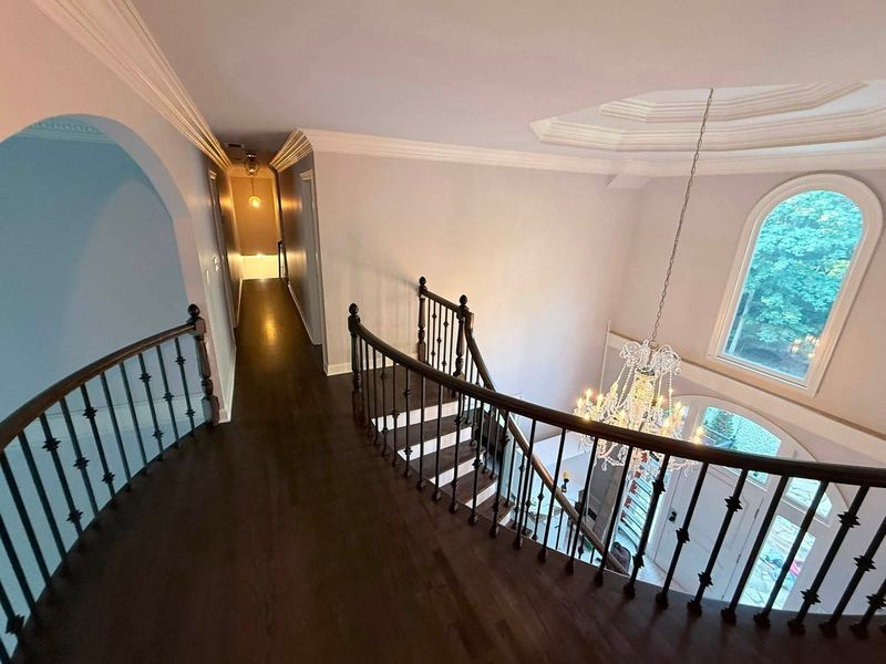 Upstairs landing with a curved iron balcony railing over a dark stained oak floor