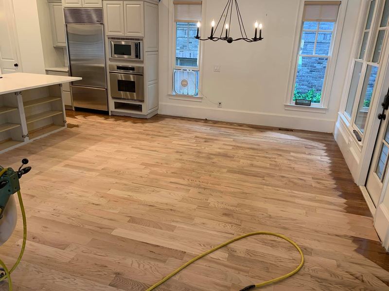 Kitchen and dining floor sanded to bare wood with a sander cord on the floor