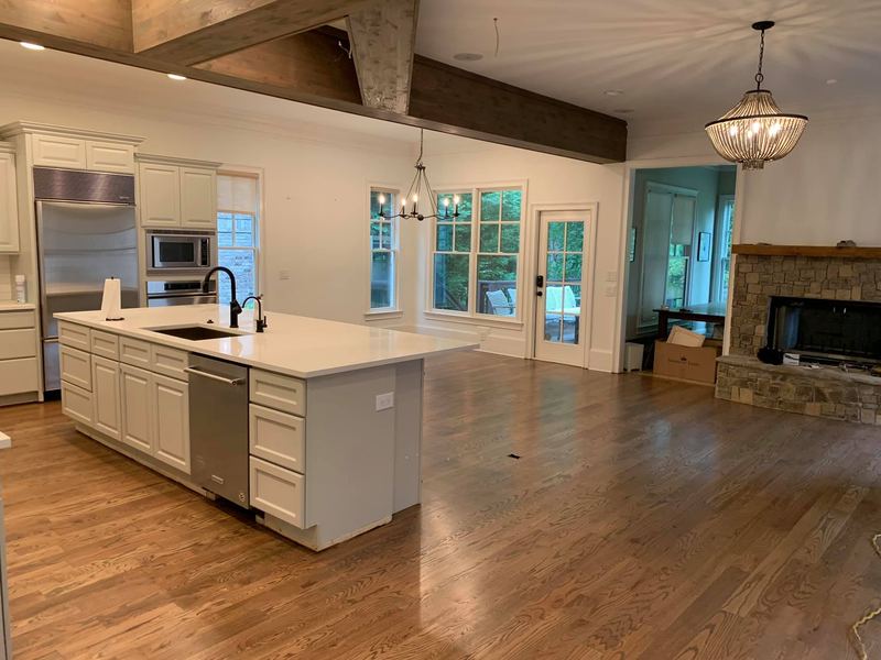 Kitchen island and family room with a stone fireplace over a freshly finished oak floor