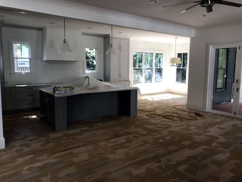 New-construction kitchen with new oak boards partway through sanding