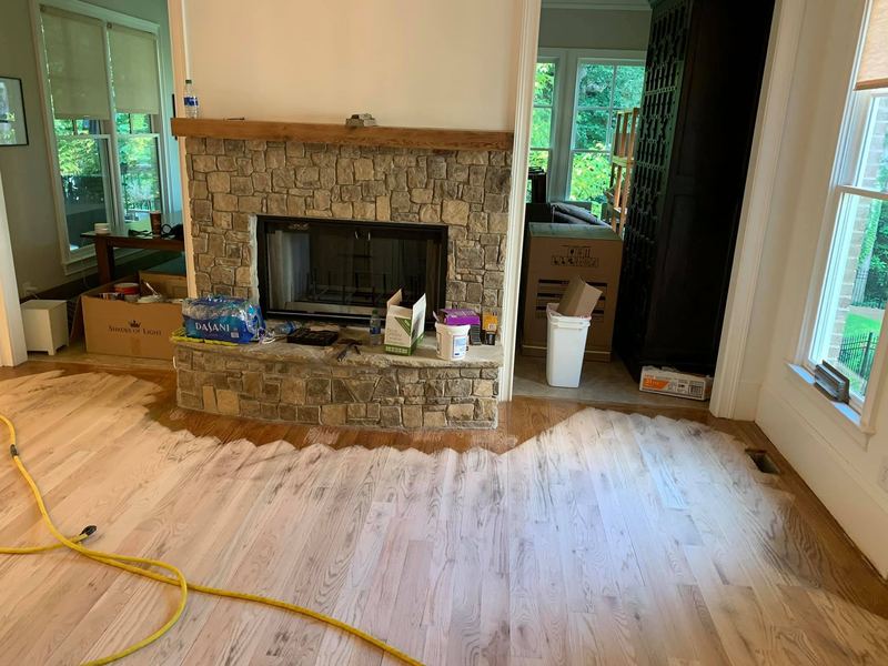 Freshly sanded floor around a stone fireplace hearth